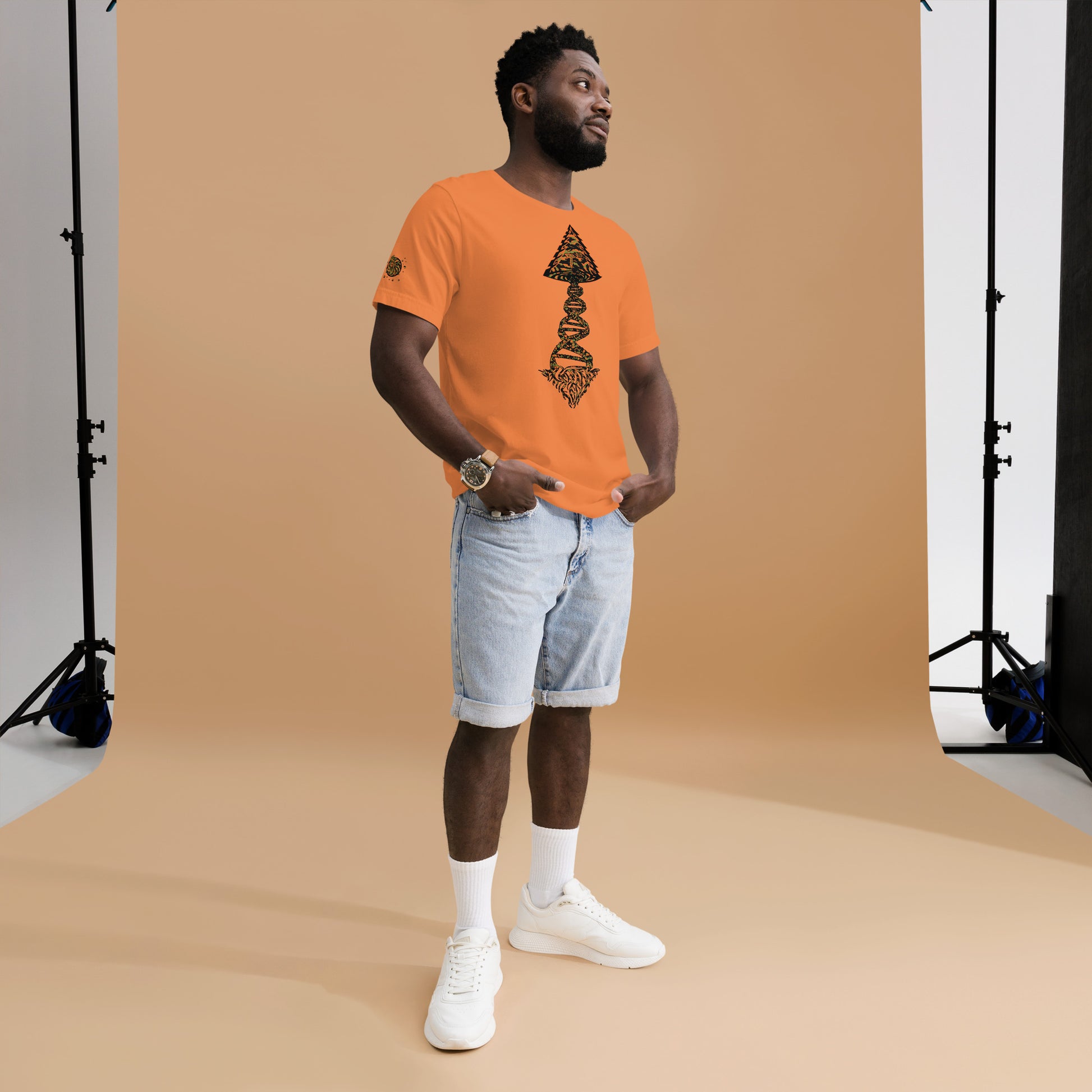 Man wearing an orange Tango Tree Of Life t-shirt, styled with denim shorts and sneakers, posing against a neutral backdrop.